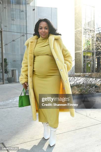 Guest wears a butter yellow plush faux fur coat with a coordinating mid-length turtleneck dress, a white slouchy boot, and the Kate Spade Green mini...