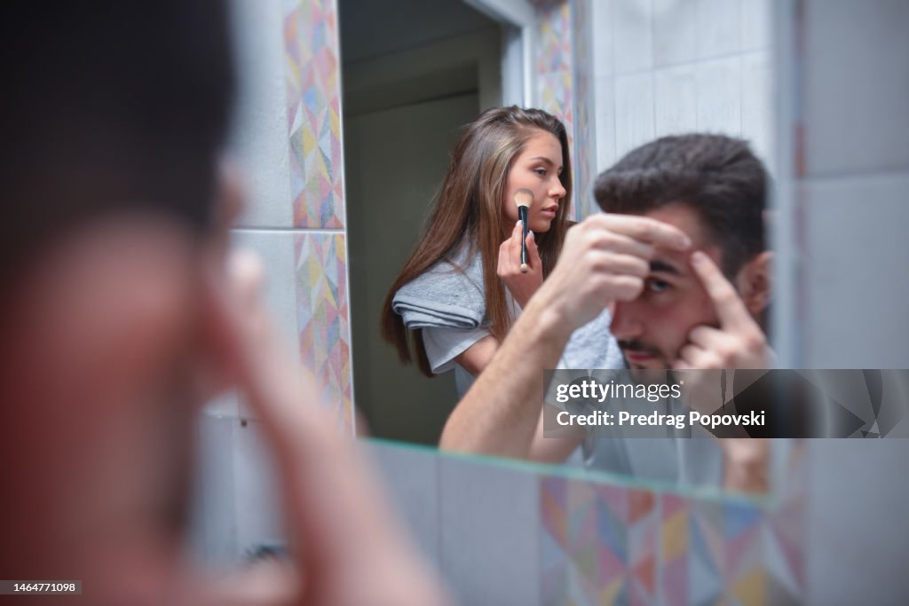 Young couple in bathroom taking skin care