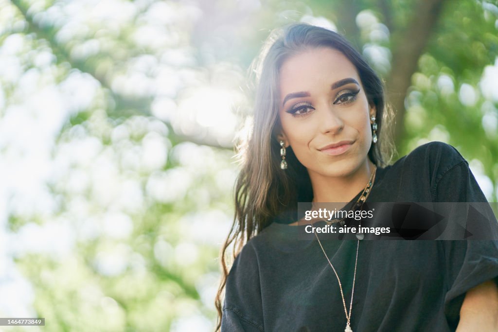 Beautiful Spanish woman wearing a black sweater, a collar and her loose hair under Sunlights. A Spanish black haired woman with loose hair photo taken from a low angle.