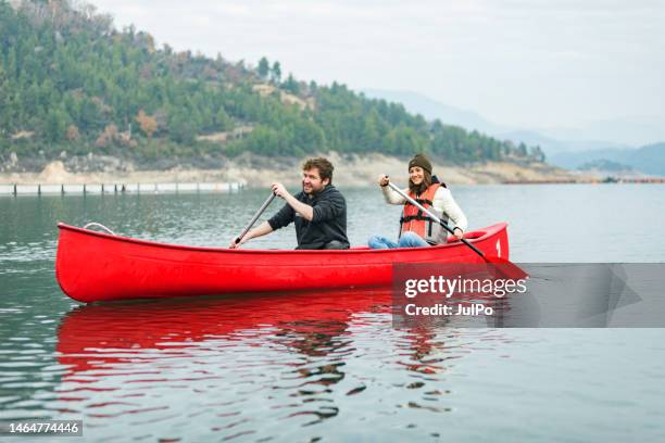 young adult couple canoeing at the lake - young couple red sunny stock pictures, royalty-free photos & images