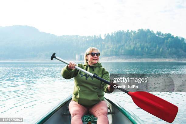 mature woman canoeing at the lake alone - seniors canoeing stock pictures, royalty-free photos & images