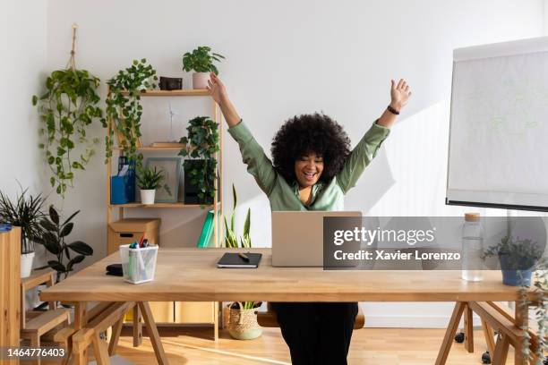 excited young latin american black businesswoman celebrating success looking laptop screen at office. - good news stock pictures, royalty-free photos & images