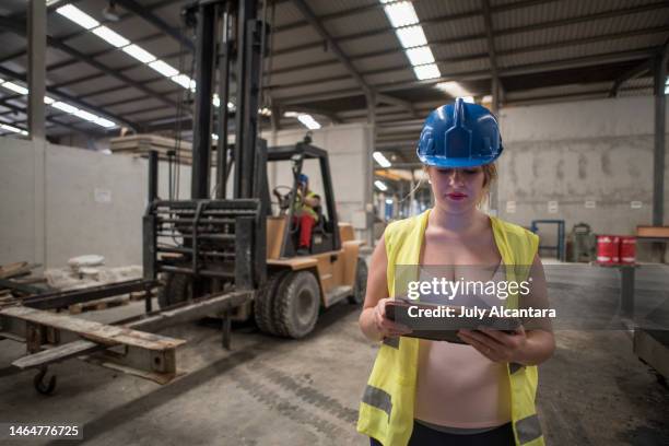 schwangere arbeiterin in betonfabrik sucht tablet mit technologie in ihrer arbeit - pregnant july 2017 stock-fotos und bilder