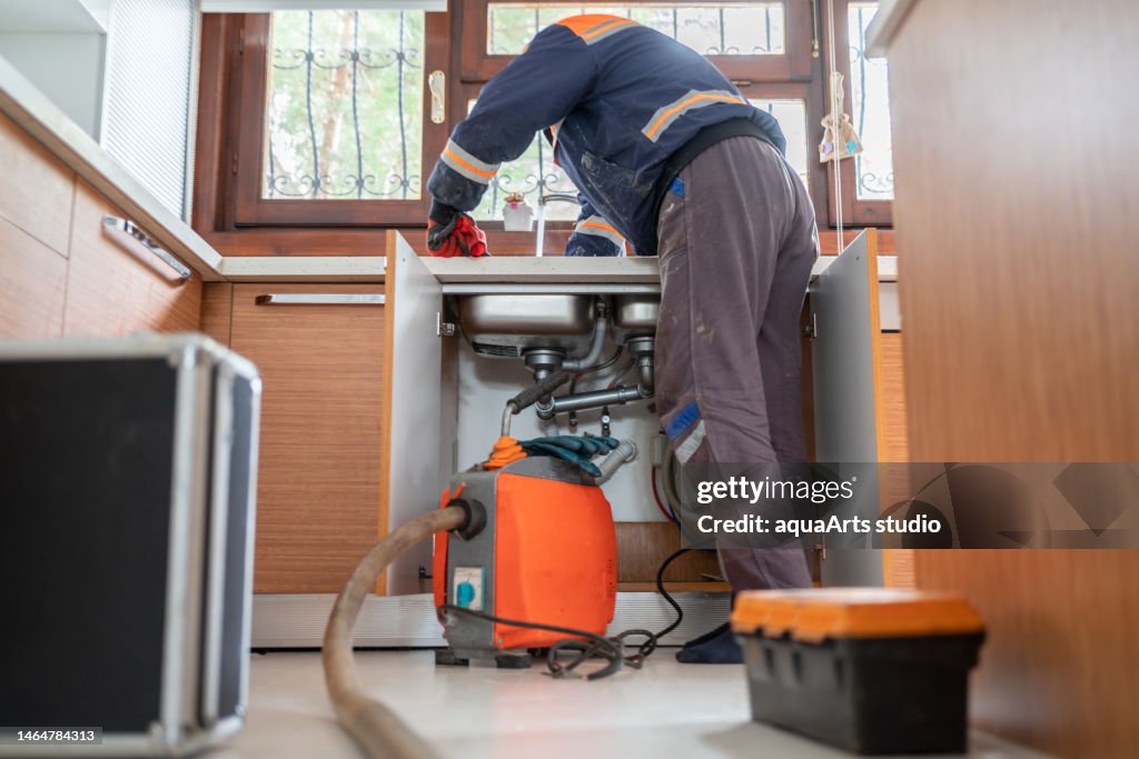Plumber Unclogging A Kitchen Sink Drain