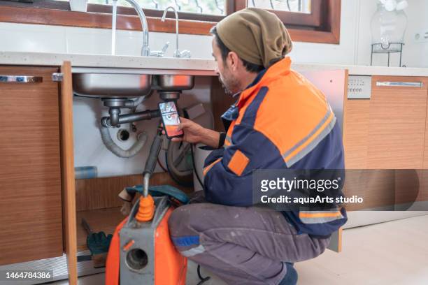 plumber unclogging a kitchen sink drain - plug hole stock pictures, royalty-free photos & images