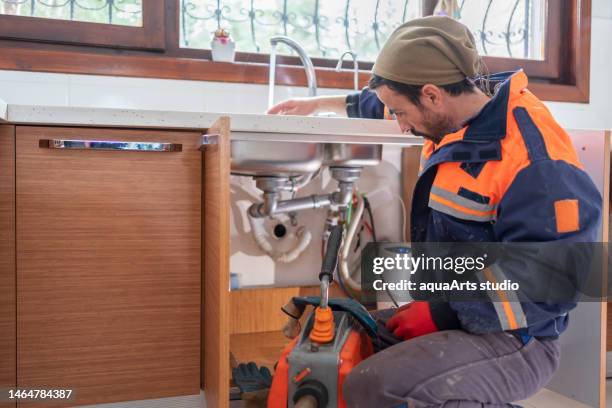 plumber unclogging a kitchen sink drain - kitchen drain stock pictures, royalty-free photos & images