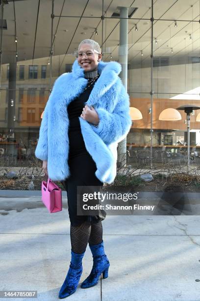 Guest wears a plush baby blue faux fur coat with velvet blue ankle boots and a pink mini-tote bag at the Kate Spade New York presentation during New...