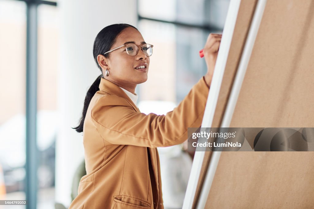Creative woman, meeting and writing on Flipchart for team building, coaching or activity ideas at office. Happy female employee in presentation using board to write idea or FAQ for company startup