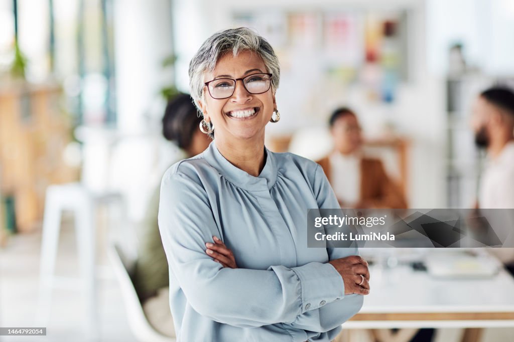Leadership, portrait and business woman in the office with crossed arms, smile and confidence. Happy, leader and professional senior female employee or company manager standing in modern workplace.