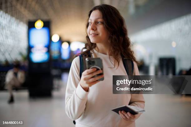 happy and excited teenage girl using mobile phone at the airport - wanderer stock pictures, royalty-free photos & images