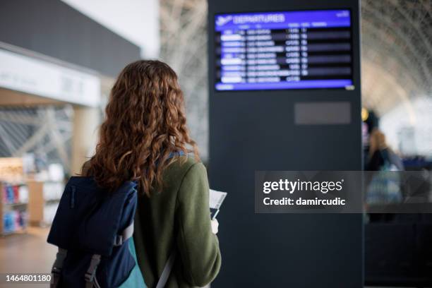 weibliche touristin, die auf die ankunfts- und abreisetafel schaut - ankunfts und abfahrtstafel stock-fotos und bilder