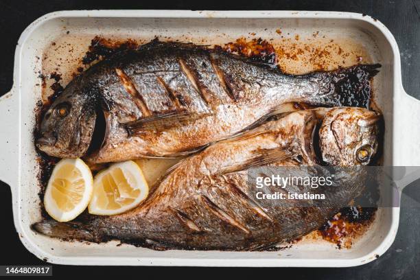 baked sea bream dorado fish in baking tray viewed from above - dolphin fish stock pictures, royalty-free photos & images