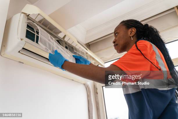 black female technician service open air conditioner indoor for checking and repairing - hot and new stock pictures, royalty-free photos & images