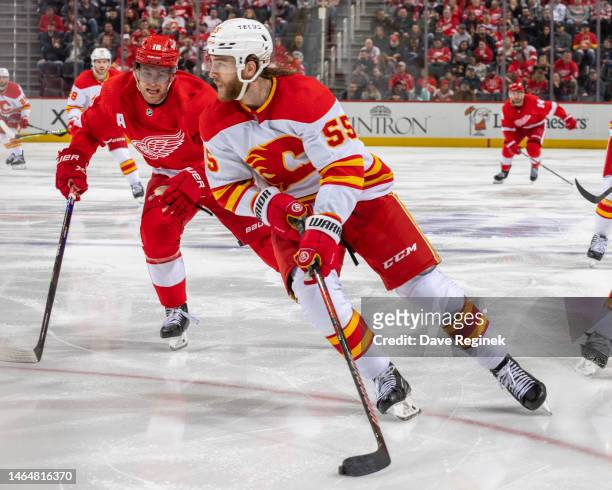 Noah Hanifin of the Calgary Flames controls the puck in front of Andrew Copp of the Detroit Red Wings during the third period of an NHL game at...