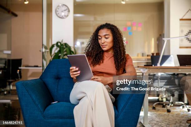 young businesswoman tablet computer while sitting on armchair at office - een tablet gebruiken stockfoto's en -beelden