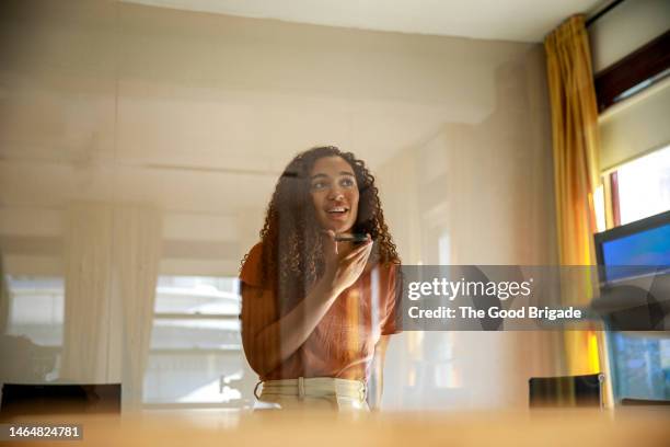 young woman talking on smart phone in conference room - speech recognition stock pictures, royalty-free photos & images