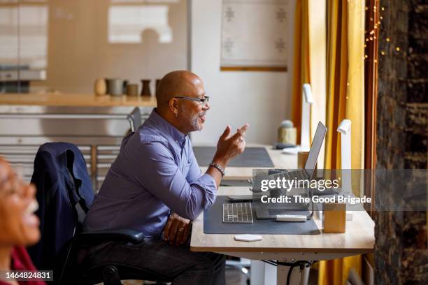 side view of businessman gesturing while doing video call through laptop at office - two people video conferencing stock pictures, royalty-free photos & images