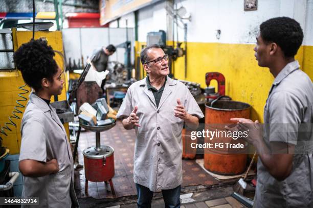 auto mechanic senior man talking with his assistants on a repair shop - werk in uitvoering stockfoto's en -beelden