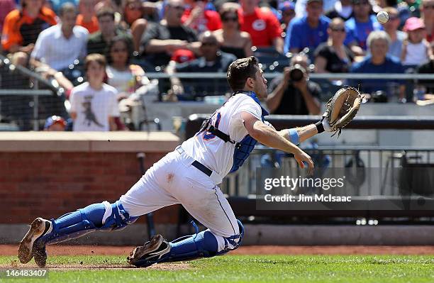 Josh Thole of the New York Mets dives to catch a seventh inning bunt attempt by Wilson Valdez of the Cincinnati Reds at Citi Field on June 17, 2012...