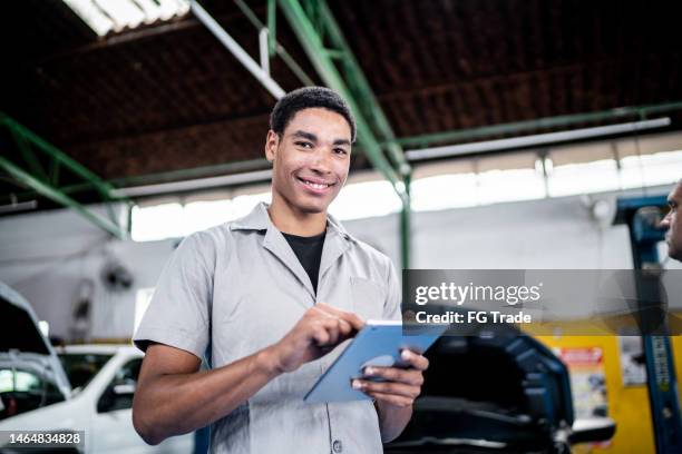portrait of an auto mechanic man using a digital tablet on the repair shop - car mechanic stock pictures, royalty-free photos & images