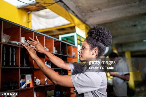 auto mechanic woman organizing the shelf on a repair shop - reserveonderdeel stockfoto's en -beelden