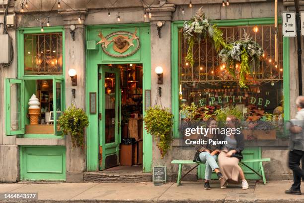 dos mujeres se ríen en un banco frente a un café restaurante tradicional en el casco antiguo de montreal, quebec canadá - montreal fotografías e imágenes de stock