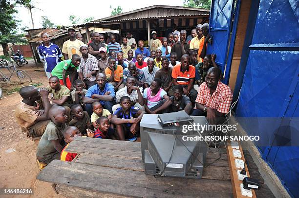 Residents of Ivory Coast town of Guiglo in the West of the country gather around a television to look at the 2012 EURO football tournament match...