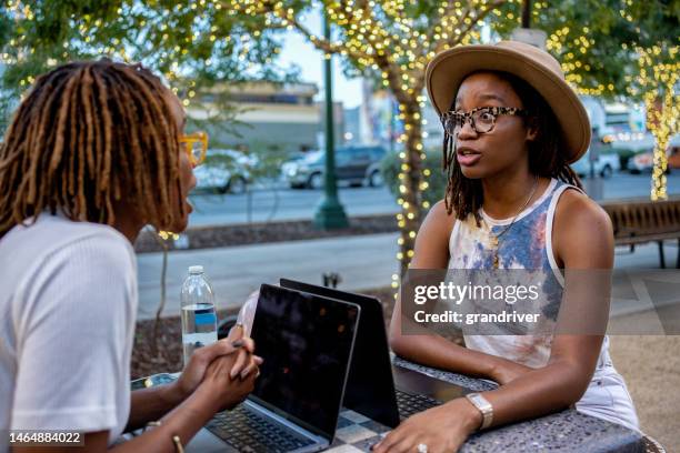 african-american twin sisters in their twenties enjoying a deep conversation at a table in a  park - sisters fighting stock pictures, royalty-free photos & images