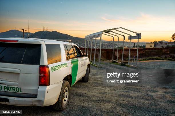 offizielles fahrzeug des us-grenzschutzes in der nähe der internationalen grenzmauer zwischen den vereinigten staaten und mexiko in tecate california in der abenddämmerung mit hübscher wolkenlandschaft geparkt - mexico border wall stock-fotos und bilder