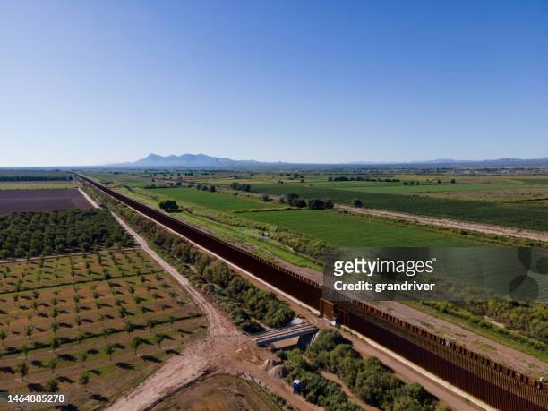 grenzmauer zwischen chihuahua mexiko und texas in fort hancock mit obstgarten und landwirtschaftlichen feldern an einem sonnigen späten nachmittag - mexico border wall stock-fotos und bilder