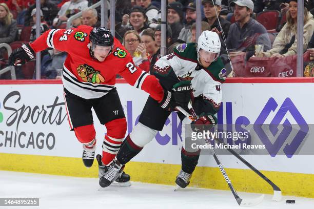 Sam Lafferty of the Chicago Blackhawks and Juuso Valimaki of the Arizona Coyotes battle for control of the puck during the second period at United...