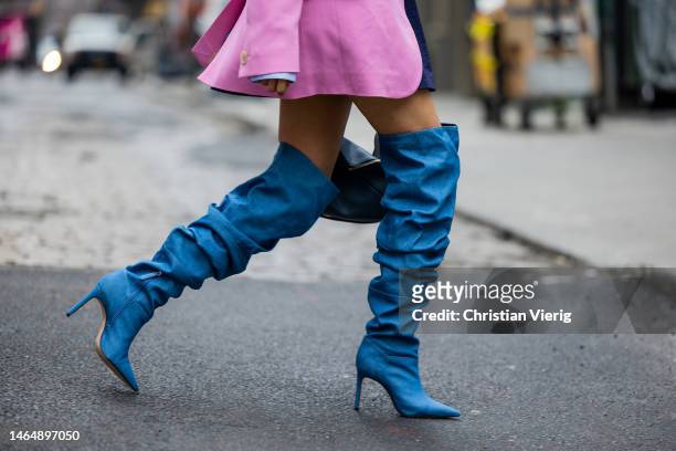 Malvika Sheth wears Schutz over knees boots, Loewe bag, pink blazer, skirt, blue button shirt, tie during New York Fashion Week on February 10, 2023...