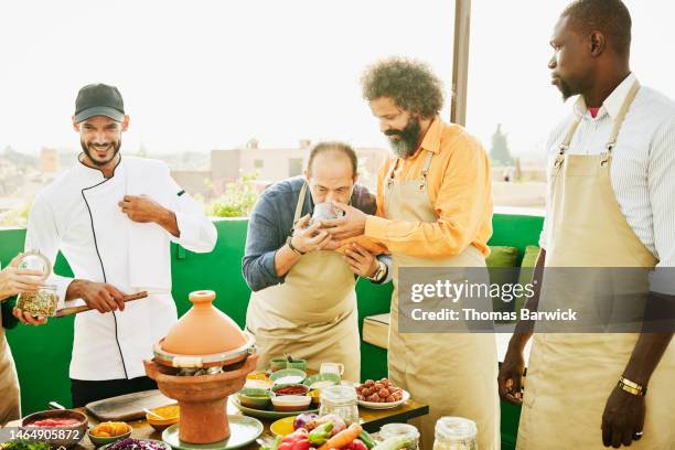 medium shot of students smelling spices during rooftop cooking class - maroc school stock-fotos und bilder