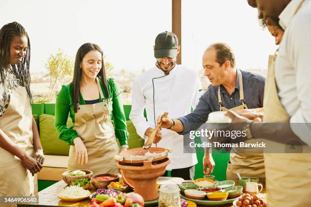 medium shot of student stirring onions in tajine during cooking class - marrakech spice stock pictures, royalty-free photos & images