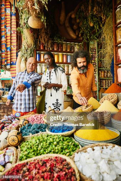 medium shot couple and spice shop owner in the souks of marrakech - marrakech spice stock pictures, royalty-free photos & images