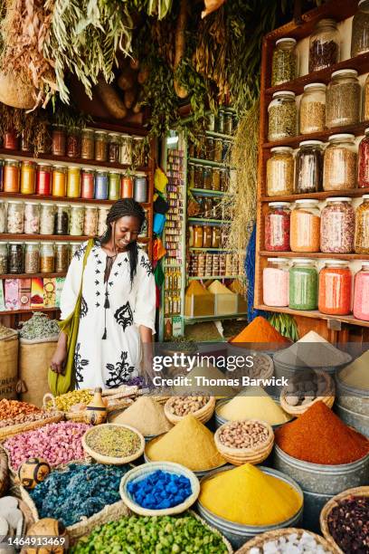 wide shot of woman shopping in spice shop in the souks of marrakech - africa flora fotografías e imágenes de stock