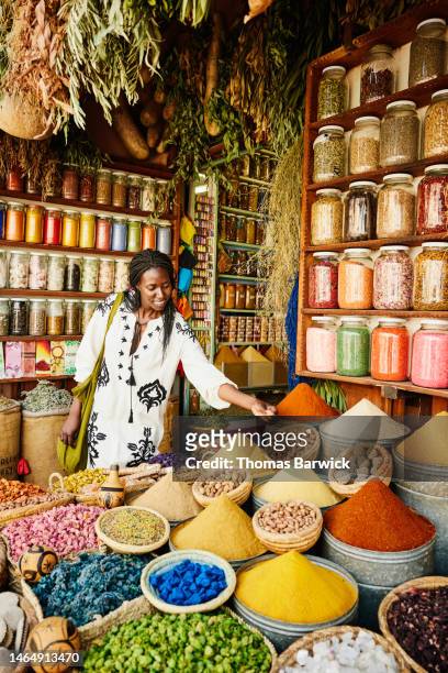 wide shot of woman shopping in spice shop in the souks of marrakech - marrakech spice stock pictures, royalty-free photos & images