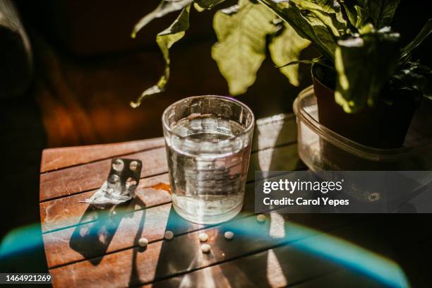 glass of water and pills and blister with hard shadows - medicare supplement stock pictures, royalty-free photos & images