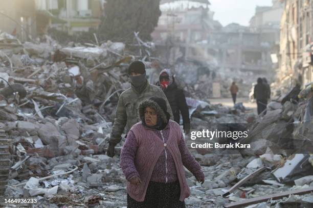 People walk past collapsed buildings on February 11, 2023 in Hatay, Turkey. A 7.8-magnitude earthquake hit near Gaziantep, Turkey, in the early hours...