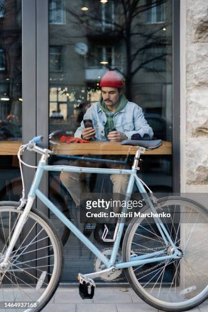 self-sufficient pensive man hipster sits inside cafe and drinking coffee checking news on phone - georgian man stock pictures, royalty-free photos & images