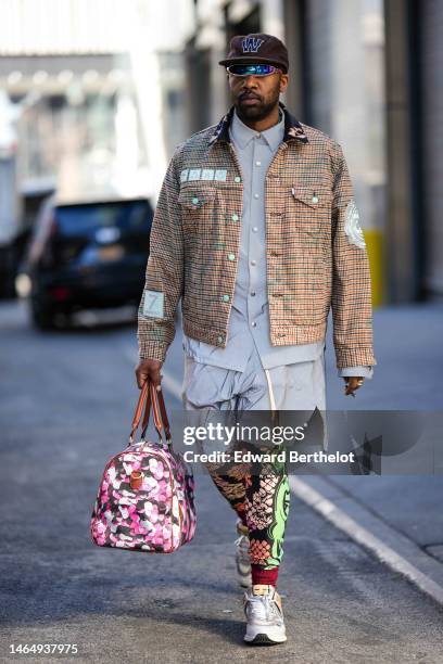 Guest wears a dark brown with blue embroidered W pattern cap, silver sunglasses, a pale gray oversized shirt, matching pale gray sport shorts, a...