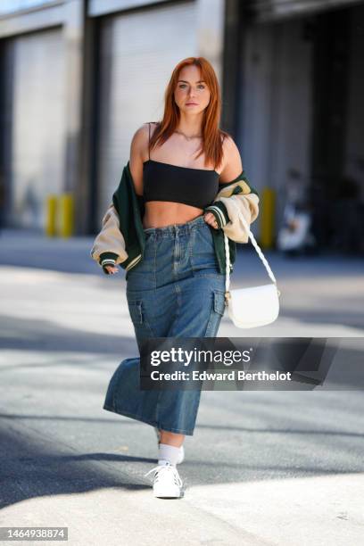 Guest wears a black square neck / cropped tank-top, a dark green felt wool with beige shiny leather sleeves teddy coat, a blue denim long skirt, a...