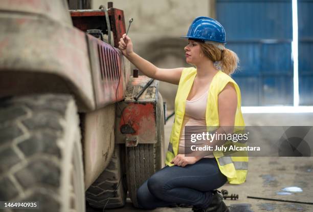 mujer embarazada en fábrica reparando viejo vehículo montacargas, reparando vehículo en almacén de la industria cementera - pregnant july 2017 fotografías e imágenes de stock