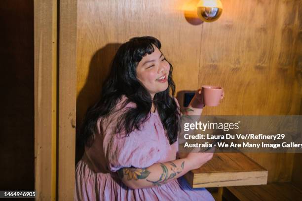 young tattooed woman laughing in cafe drinking a coffee - melbourne cafe stock-fotos und bilder