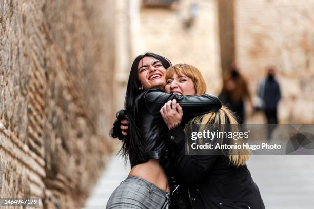 blonde and brunette woman hugging each other happily. concept of friendship and happiness. - travel loyalty stock pictures, royalty-free photos & images