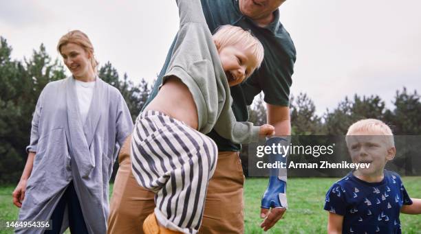 family with two sons having fun in nature. father is wearing orthopedic cast on broken and injured arm - broken arm stock pictures, royalty-free photos & images