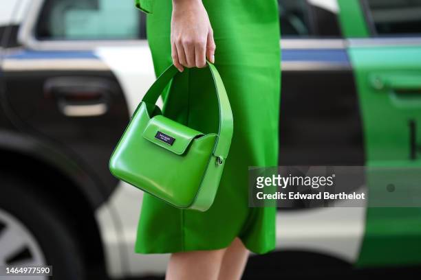 Guest wears a green satin high waist / knees skirt, a green shiny leather handbag from Kate Spade, outside Kate Spade, during New York Fashion Week,...