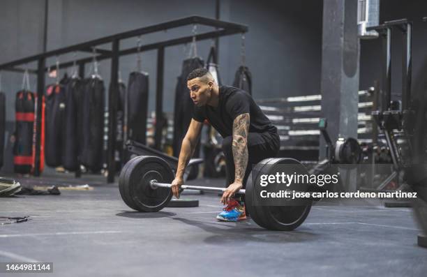 young fit hispanic man in the gym lifting heavy barbell deadlifts - barbell stock pictures, royalty-free photos & images