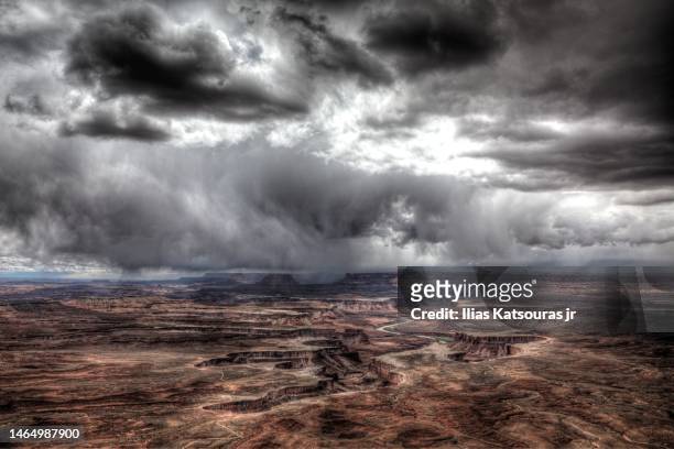 view of colorado river flowing in canyonlands canyon under dramatic cloudy sky - utah stock pictures, royalty-free photos & images