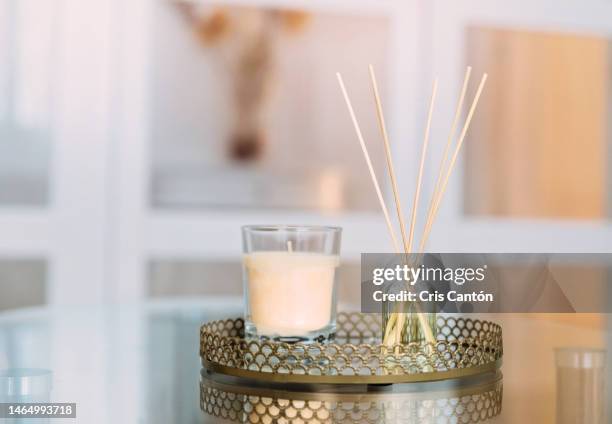 glass reed diffuser and scented candle in living room - scent home stock-fotos und bilder